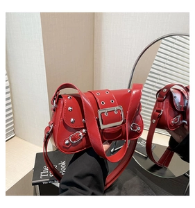 Détail d'un sac à bandoulière punk rouge en cuir brillant avec des rivets métalliques