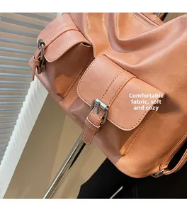 Detail view of pink orange oiled leather tote showing soft texture and metal buckles