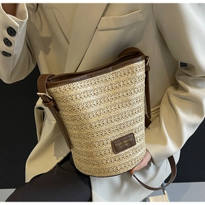 Detail shot of the woven straw texture and premium brown leather label on the bucket bag