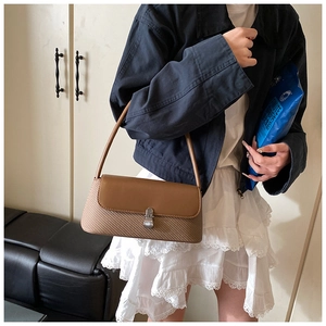 Détail d'un sac porté épaule en cuir marron et tissage avec boucle en métal argent