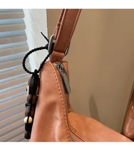 Detail of silver smooth zipper and metal hardware on orange leather tote bag