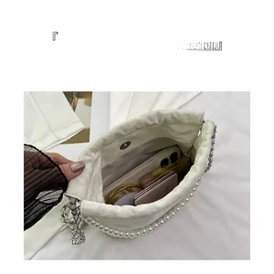 Detailansicht der weißen Rafftasche mit Perlen zeigt Stauraum für Handy und Make-up