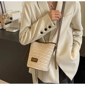 Dettaglio della borsa a secchiello in paglia con finiture in pelle e logo impresso