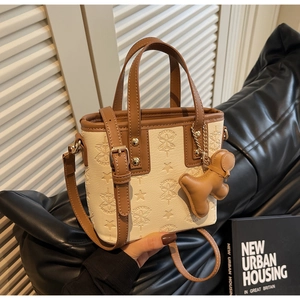 Détail du sac seau crème avec gaufrage en étoile et accessoire charm chien en cuir