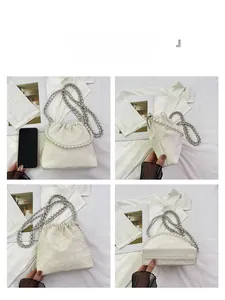 Details der weißen Faltenbeuteltasche mit Perlengriff und Metallkettenriemen