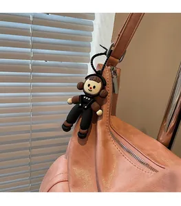 Close-up of a cute cartoon doll charm with black bead chain on a pink leather tote bag