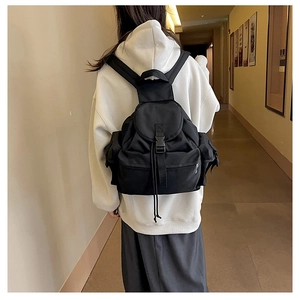 Detailed view of black nylon backpack with multiple pockets and plastic buckle closure
