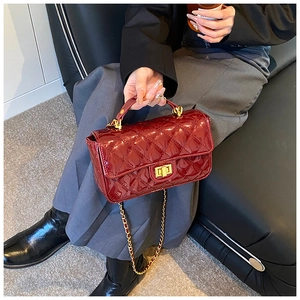 Detail view of burgundy patent leather crossbody bag with quilted diamond pattern and gold lock