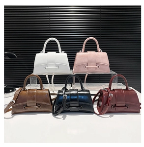 Detail of five glossy wrinkled leather trapezoid handbags with signature wrap-around buckle