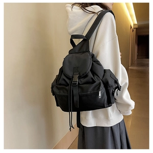 Detailed side view of a black nylon backpack featuring buckle straps and drawstring closure