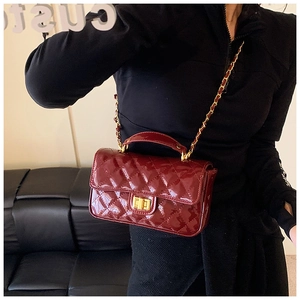 Detail of burgundy patent leather quilted crossbody bag with gold-tone twist lock and chain
