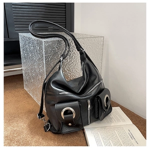 Detail of black pebbled leather tote with silver zippers and large metal ring decoration