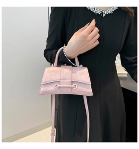 Detail of pink glossy leather handbag with wrinkled texture shown on black dress