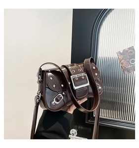Detail of dark brown punk style shoulder bag with silver buckle and metal rivets