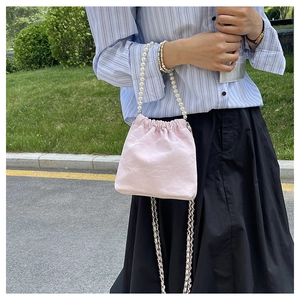 Rosafarbene Kordeltaschen-Handtasche mit Perlengriff und geflochtenem Kettenriemen im Freien