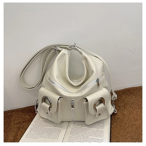 Close-up of beige tote bag with lychee texture and metallic silver rings on a book
