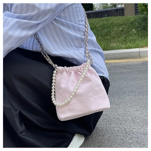 Detail der hellrosa Kordelzug-Beuteltasche mit Perlengriff und geflochtener Metallkette