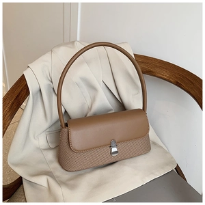 Détail d'un sac bandoulière contrasté avec rabat en cuir marron et texture tissée