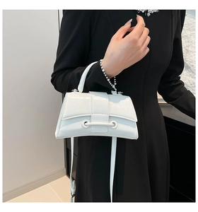 Detail showing white crocodile texture and unique curved base of the small leather handbag