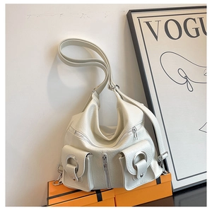 Detail of a creamy white textured tote bag with silver rings and dual front pockets