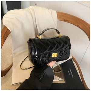 Close-up of black patent leather crossbody bag featuring quilted patterns and gold lock