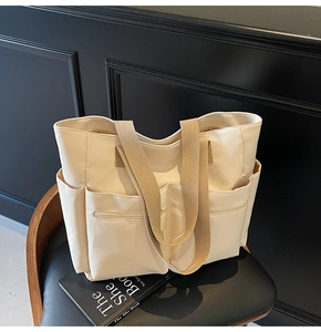 Close-up of cream canvas tote bag showing multiple front pockets and woven straps