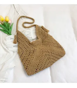 Vue détaillée du sac tissé à la main avec motif ajouré, pompon décoratif et anses souples