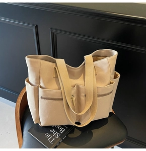 Detail of canvas tote bag showing two front zipper pockets and wide shoulder straps