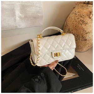 Detail of white patent leather crossbody bag featuring quilted stitching and gold chain