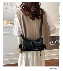 Close-up of black glossy oil wax leather shoulder bag with vintage moto-style pockets