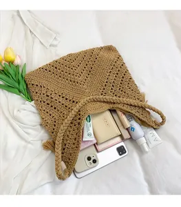 Détail du sac en paille tressée avec pompons montrant l'intérieur spacieux du fourre-tout