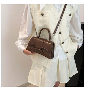 Deep brown square handbag detail showing glossy leather texture and cross-body strap