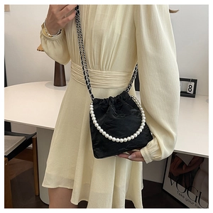 Detailaufnahme der schwarzen Satin-Beuteltasche mit Perlengriff und Metallkettenriemen
