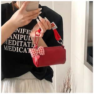 Dettaglio della mini borsa rossa in pelle con fiocco a quadretti e manico in corda