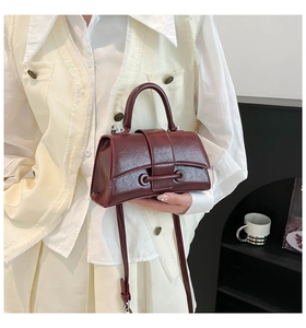 Detail of burgundy patent leather handbag with pleated texture and adjustable strap