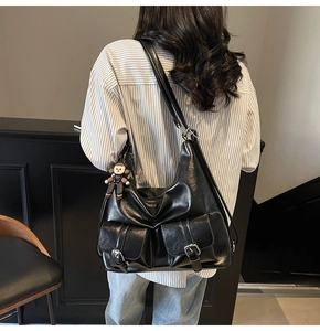Detail of hobo tote bag featuring front flap pockets and a small character charm