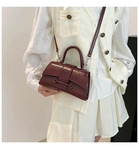 Close-up of wine red hourglass bag featuring leather texture and decorative belt strap