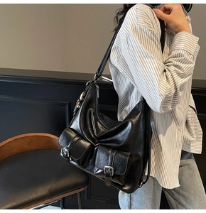 Detail view of glossy black leather tote bag with functional pockets and silver buckles