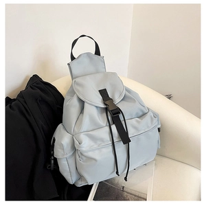 Detail view of a light blue nylon backpack with buckle flap and large front pocket