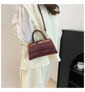 Detail of a vintage dark red glossy leather crossbody bag with silver buckles and handle