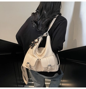 Detail of beige oil wax leather tote bag with front pockets on a model wearing jeans