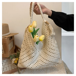 Détail du tissage ajouré et de la poignée en corde avec pompon sur sac au crochet