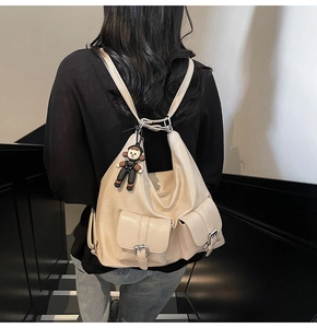 Detail view of beige oil wax leather backpack with twin pockets and a cute boy pendant
