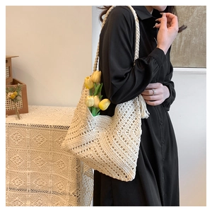 Gros plan sur un sac bandoulière beige au crochet avec motifs ajourés et glands latéraux