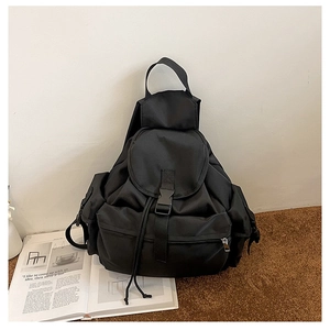 Detail of black nylon backpack with drawstring closure, multiple pockets, and buckle straps
