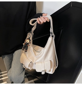 Close-up of cream oil-waxed leather hobo bag featuring multiple pockets and silver buckles