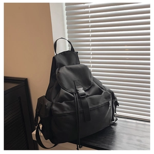 Detail view of black nylon backpack featuring buckle closure and multiple functional pockets