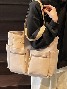 Minimalist beige canvas tote bag with multiple pockets and large storage capacity