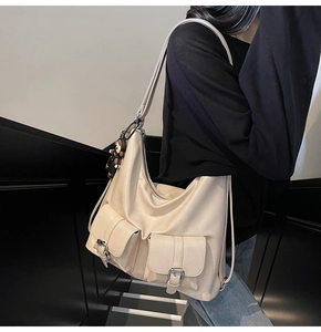 Detail view of cream faux leather tote bag with functional pockets and cute bear charm