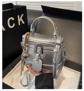 Detailed shot of silver box bag with double zippers and metallic handle in gift box